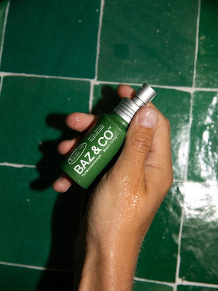 Baz & Co Skincare green 50ml natural deodorant spray bottle held in hand. Aluminium-free formula.