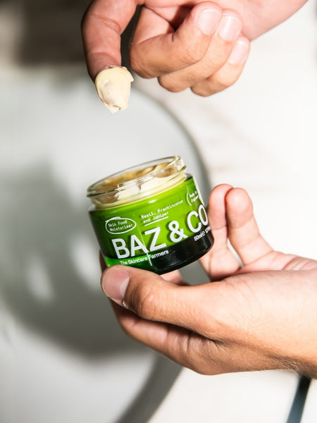 Baz & Co Skincare Skin Food Moisturiser in a green glass jar, with a dollop on a finger.