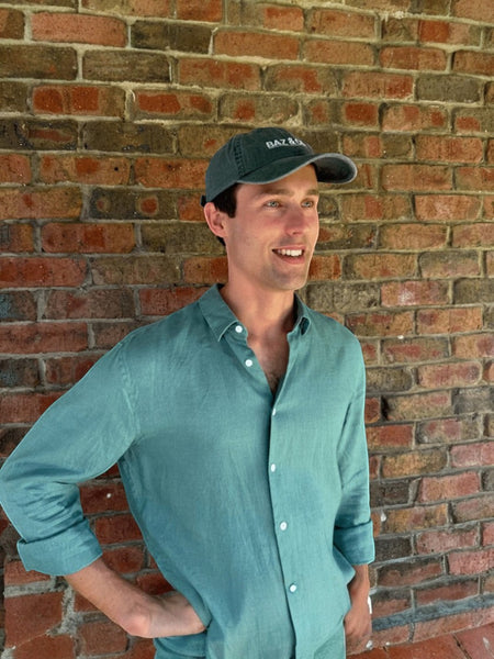 Baz & Co Skincare dark green cotton baseball cap with subtle branding, worn by a man.