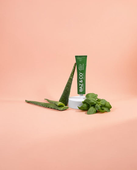 Baz & Co Skincare green tube of exfoliator cleanser with aloe vera and basil on a peach background.