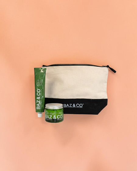 Baz & Co Skincare gift set with a canvas wash bag, exfoliator cleanser tube, and moisturiser jar on a peach background.